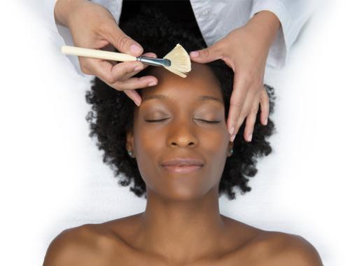 Woman with curly hair laying down as she recieves a facial treatment